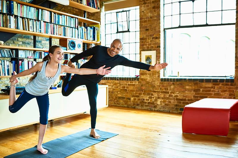 father and daughter do yoga in apartment