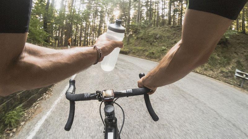 骑自行车的人看从水瓶喝水